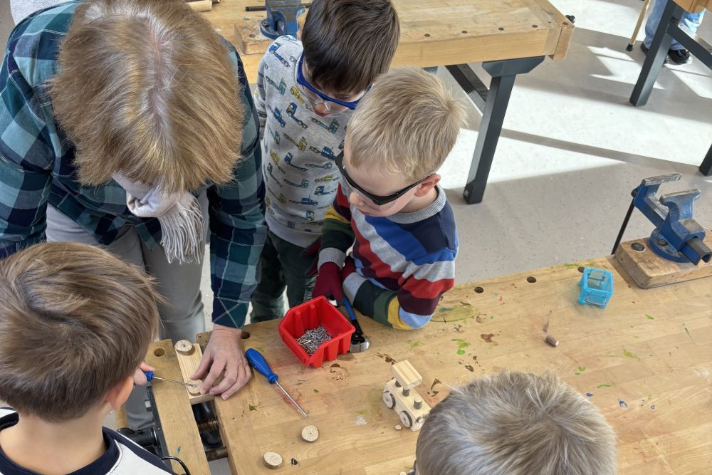 Vier Kinder arbeiten mit einer Pädagogin an der Werkbank