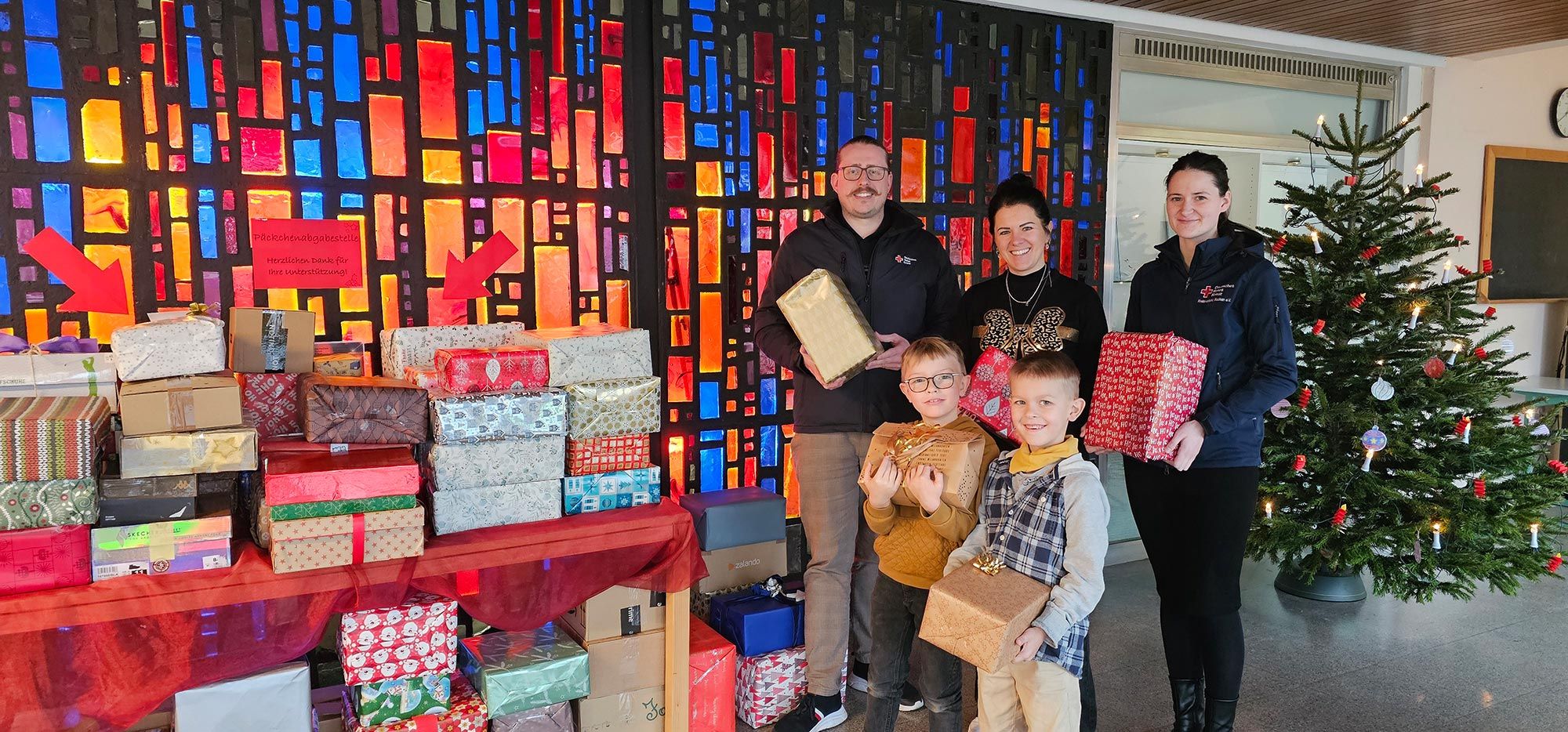 Kinder, Lehrer und Vertreter des DRK neben einem Tisch voller Geschenke
